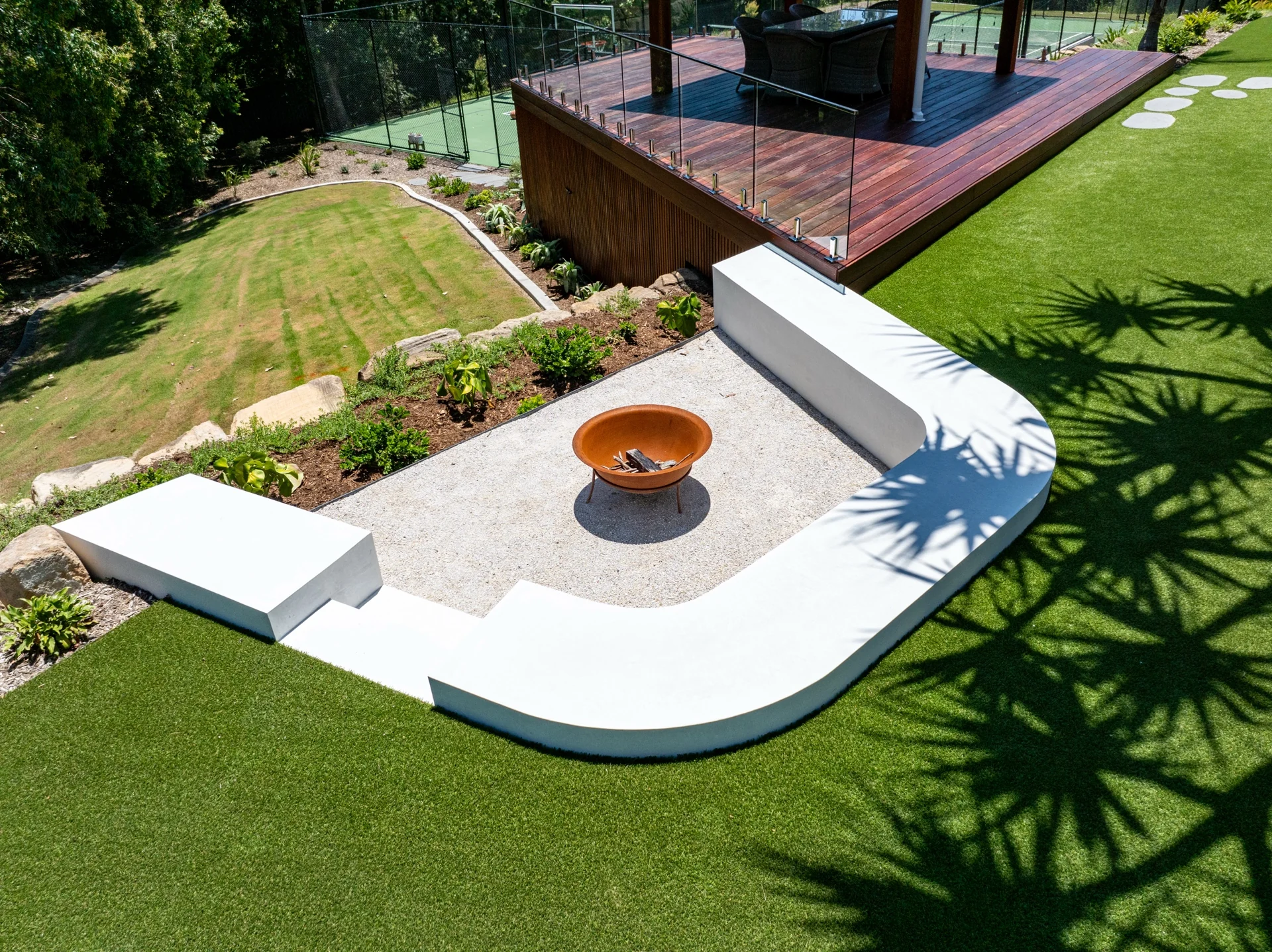 Elevated view of curved concrete seating and a fire feature within the landscape